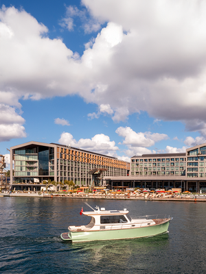 Rejs statkiem przed hotelem Rixos Tersane Istanbul w słoneczny dzień, z hotelem i przystanią nadbrzeżną w tle.