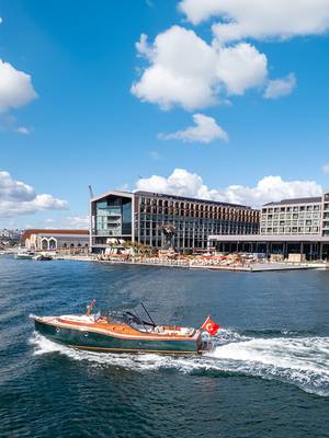 Luksusowa łódź motorowa pod turecką banderą płynąca przed hotelem Rixos Tersane Istanbul, podkreślająca nadmorskie położenie obiektu.