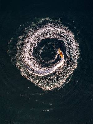 Widok z lotu ptaka na łódź tworzącą spiralny ślad na wodzie w pobliżu Rixos Tersane Istanbul, uchwycający dynamiczny moment na Złotym Rogu.