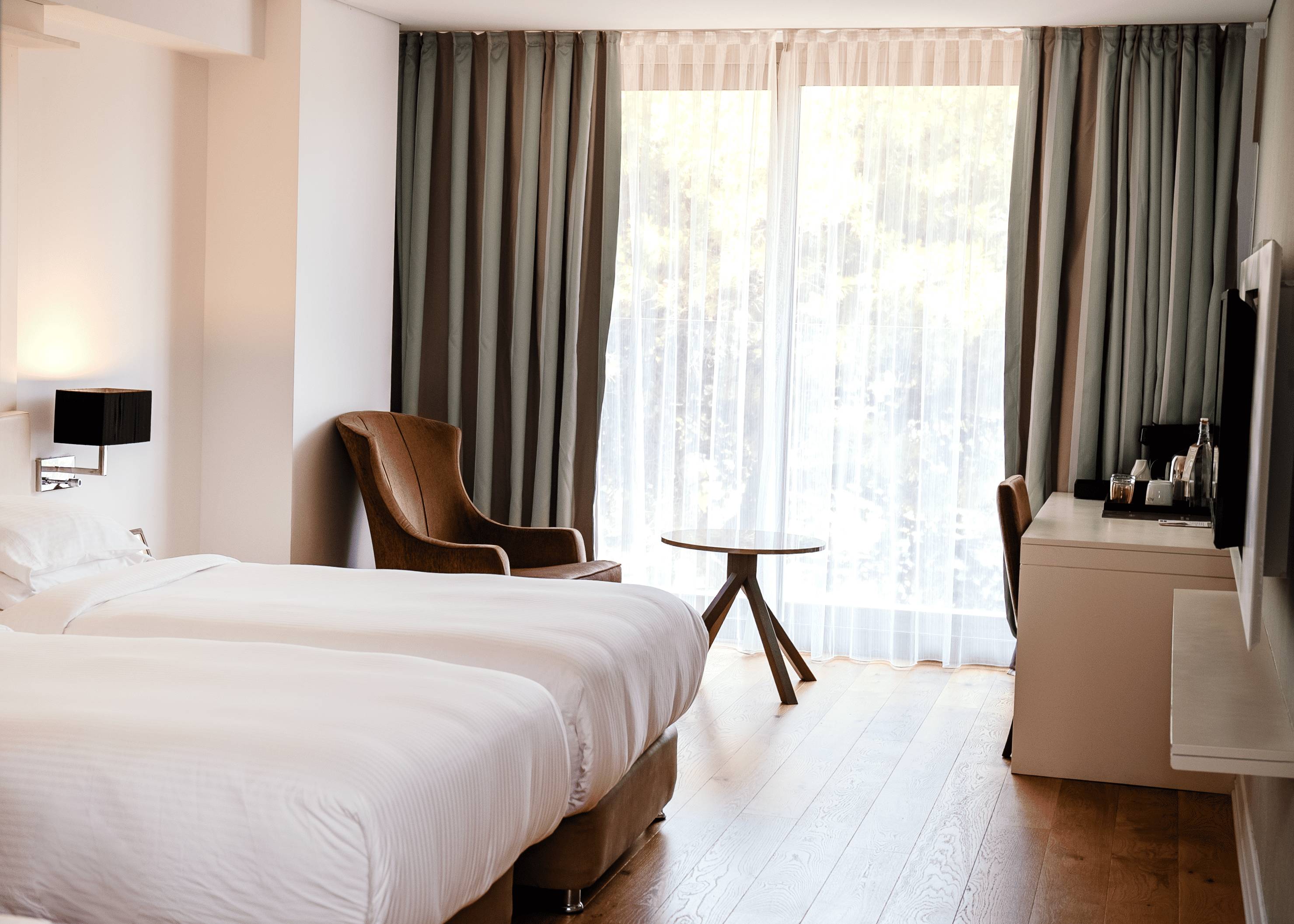 Moderna hotelska kupaonica s velikim umivaonikom, ogledalom u punoj veličini, kadom i tušem s plavim zidom s uzorkom bambusa.