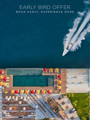 Widok z lotu ptaka na luksusowy basen w hotelu Rixos Tersane z kolorowymi parasolami nad oceanem. Łódź motorowa pędzi po błękitnej wodzie. Tekst brzmi: Oferta Early Bird. Zarezerwuj wcześniej, przeżyj więcej.