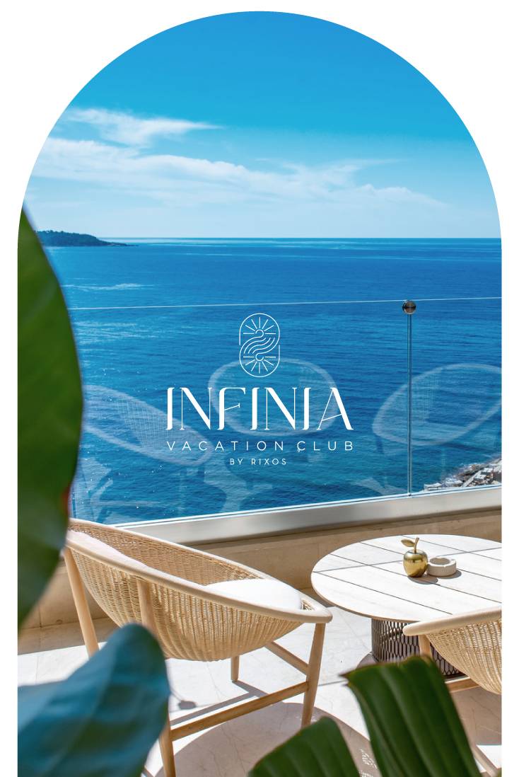 A bright balcony with two wicker chairs and a table overlooks a calm, blue ocean under a clear sky. Infinia Vacation Club by Rixos Park Belek is written on the image, while green leaves frame the tranquil scene in the foreground.