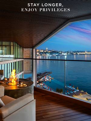 Elegancki balkon apartamentu w hotelu Rixos Tersane Istanbul z widokiem na Złoty Róg o zmierzchu, z kominkiem i panoramą miasta.