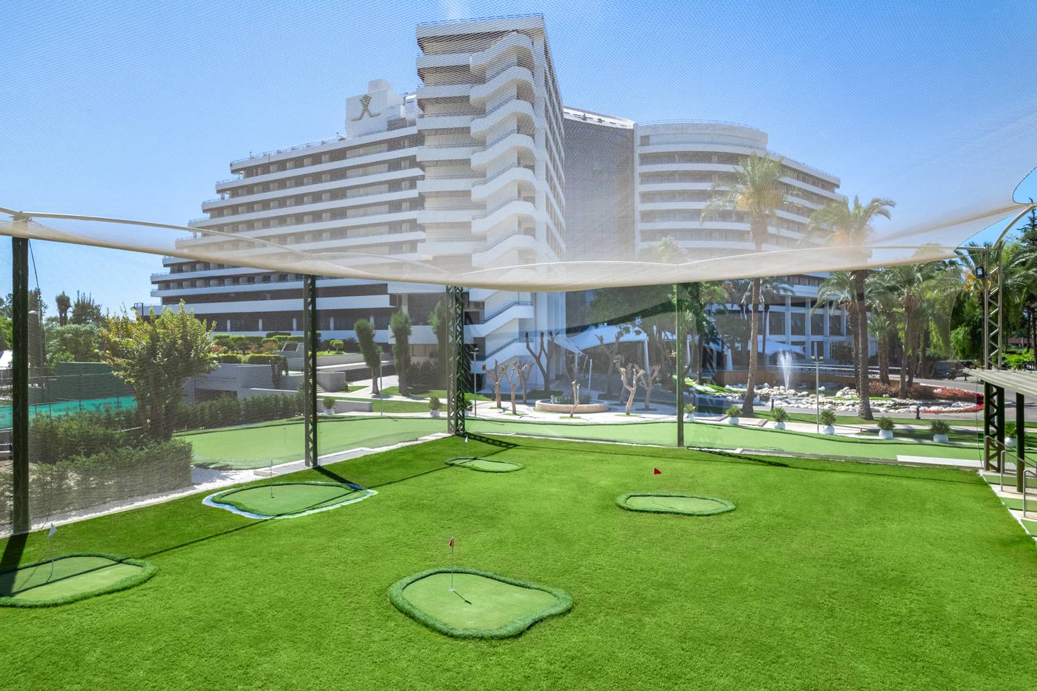 Teren za vježbanje na Rixos Golf Rangeu u Rixos Downtown Antalya sa zgradom hotela u pozadini