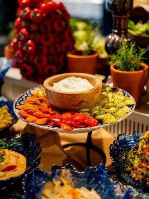 Kolorowy bufet niedzielnego brunchu w hotelu Rixos Tersane, na którym można podziwiać pięknie ułożoną tacę z różnorodnymi grillowanymi warzywami, dipami i sosami w ozdobnych miseczkach, otoczoną świeżymi ziołami i kolorowymi dodatkami.