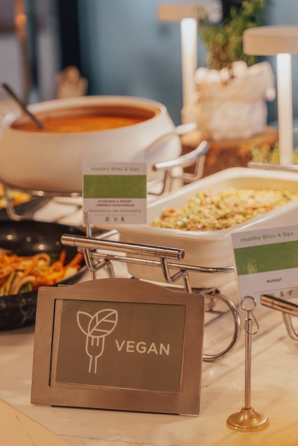 Vegan & Vegetarian Buffet at Rixos Tersane Istanbul featuring a selection of healthy dishes like avocado and lime guacamole, colorful vegetables, and salads, displayed with “Healthy Bites & Sips” and “VEGAN” signs.