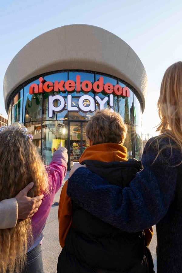 ரிக்சோஸ் டெர்சேன் இஸ்தான்புல்லில் உள்ள நிக்கலோடியன் PLAY! கட்டிடத்தின் வெளிப்புறத்தைப் பார்க்கும் ஒரு குடும்பம், பெரிய பலகையை நோக்கி ஒரு குழந்தை சுட்டிக்காட்டுகிறது.