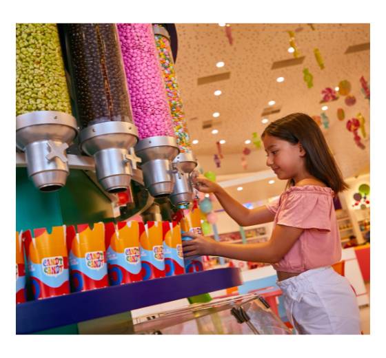 Une jeune fille remplit un gobelet griffé de bonbons provenant d'un grand distributeur de bonbons dans la boutique Candy Candy du Rixos Tersane Istanbul.
