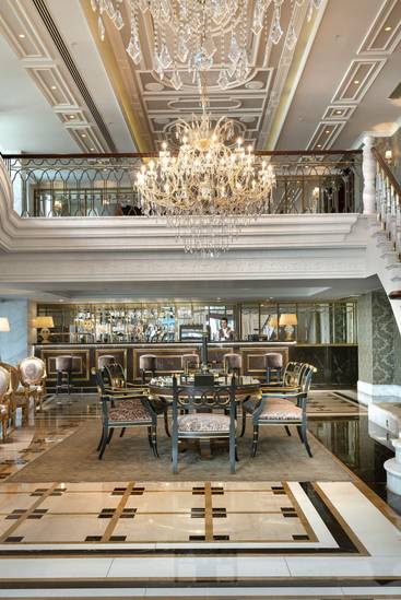 Rixos Pera Istanbul's Cafe Royal интерьерінің керемет ақ мәрмәр баспалдақтары, екінші қабаттағы әсем балконы және көрнекті хрустальды люстра бар. Бірінші қабатта жылтыратылған мәрмәр плитка, алтын екпінді отырғыш және фонда көрінетін бар аймағы бар.